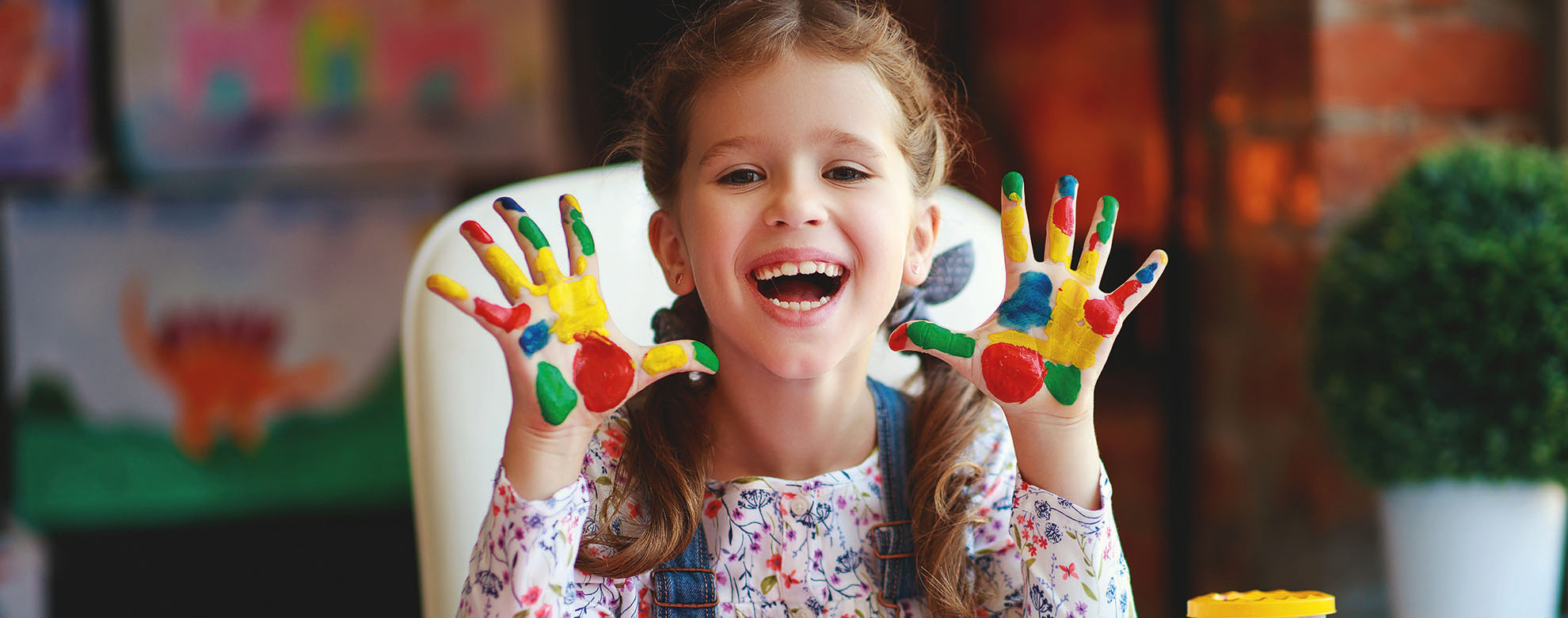 funny child girl draws laughing shows hands dirty with paint